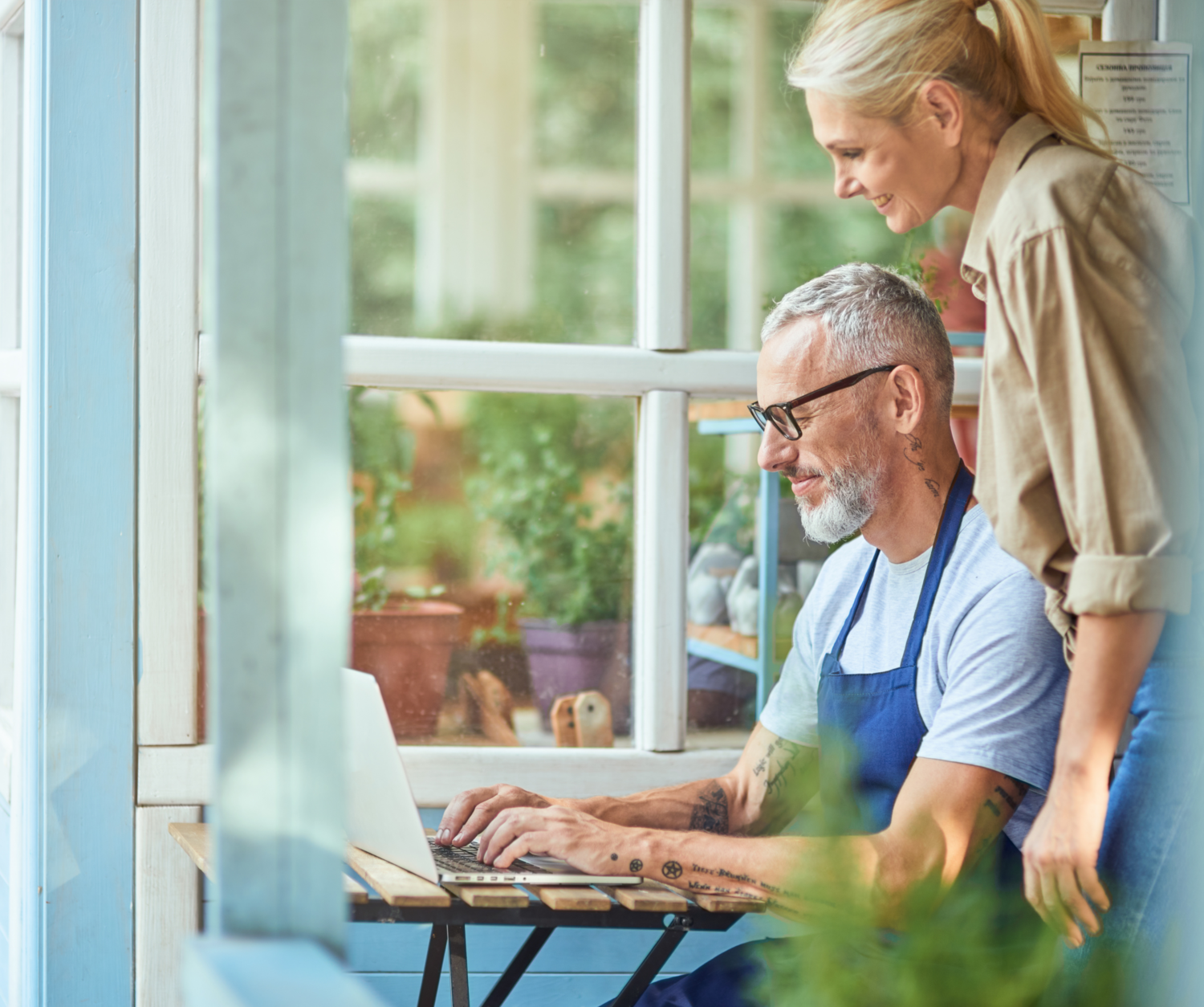 Man Working With His Laptop And A Woman Standing Next To Him