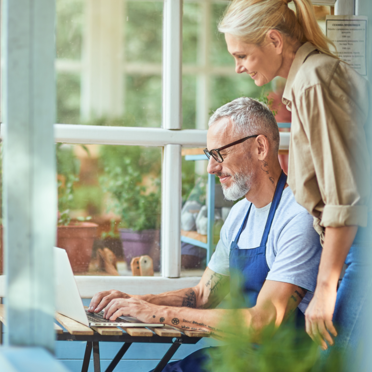 Man Working With His Laptop And A Woman Standing Next To Him